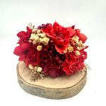 Venta de complementos de flamenca: imagen de ramillete rojo con dorado sobre superfície de madera